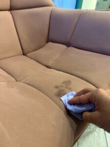 Gently blotting a couch stain that can worsen with improper cleaning 