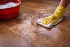 Hardwood floor with worn, dull patches caused by repeated cleaning, showing breakdown of the protective finish.